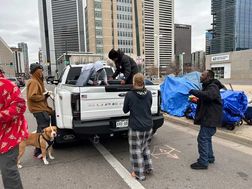 ARCM Roofing crew handing out holiday food from a pickup truck in downtown Denver